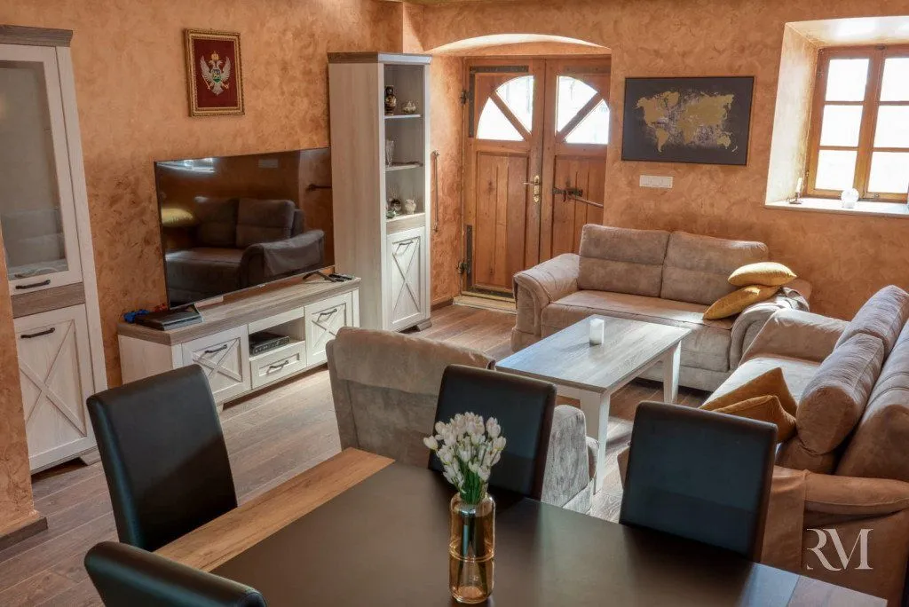 Spacious living room with sofa set, TV, and dining table.