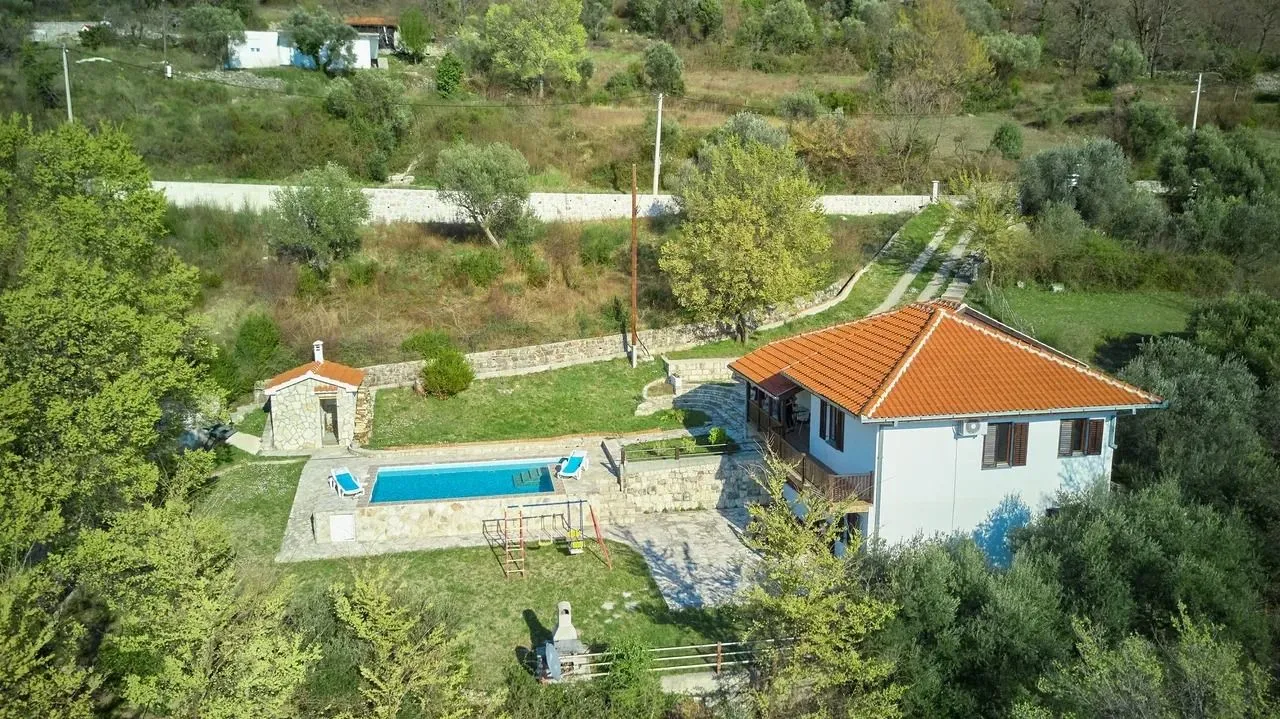 Aerial view of a house with a swimming pool and a spacious yard.