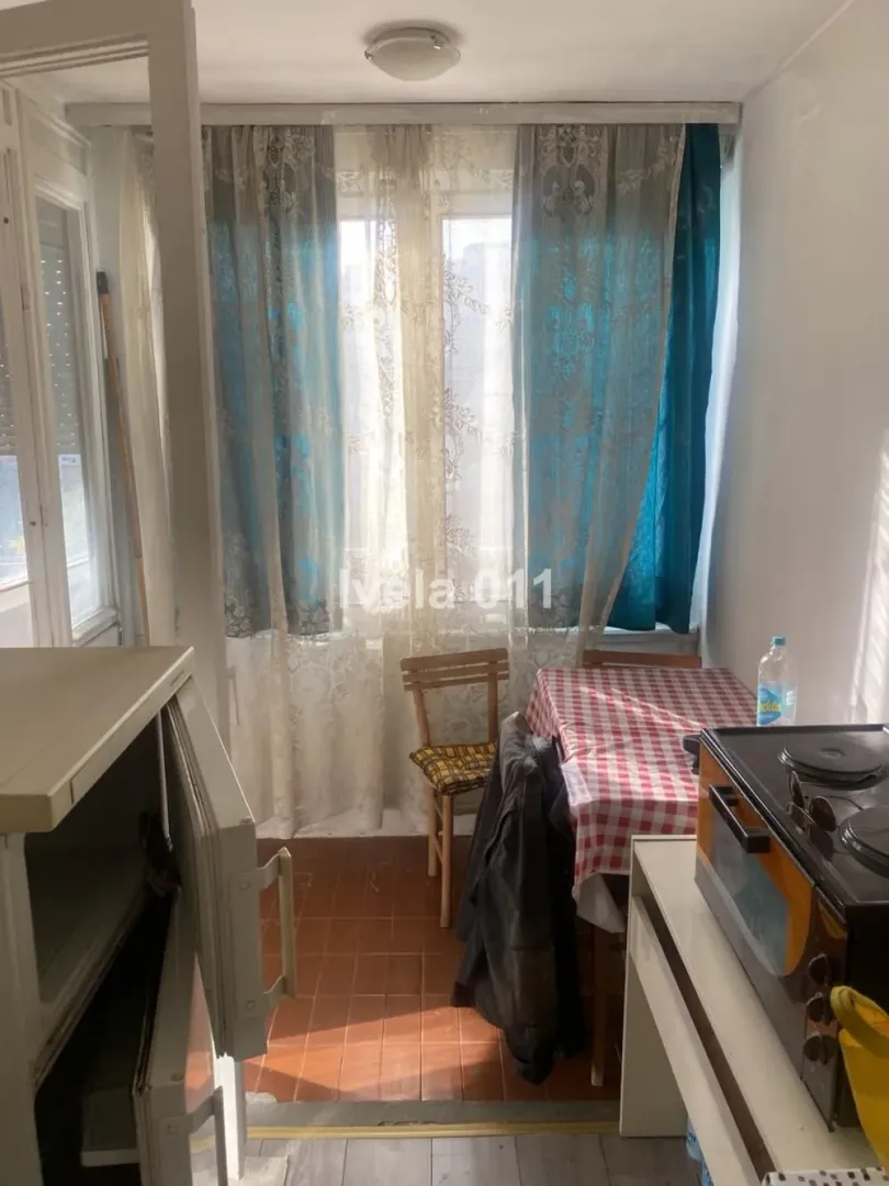 Small kitchen with a dining table and a window covered with curtains.