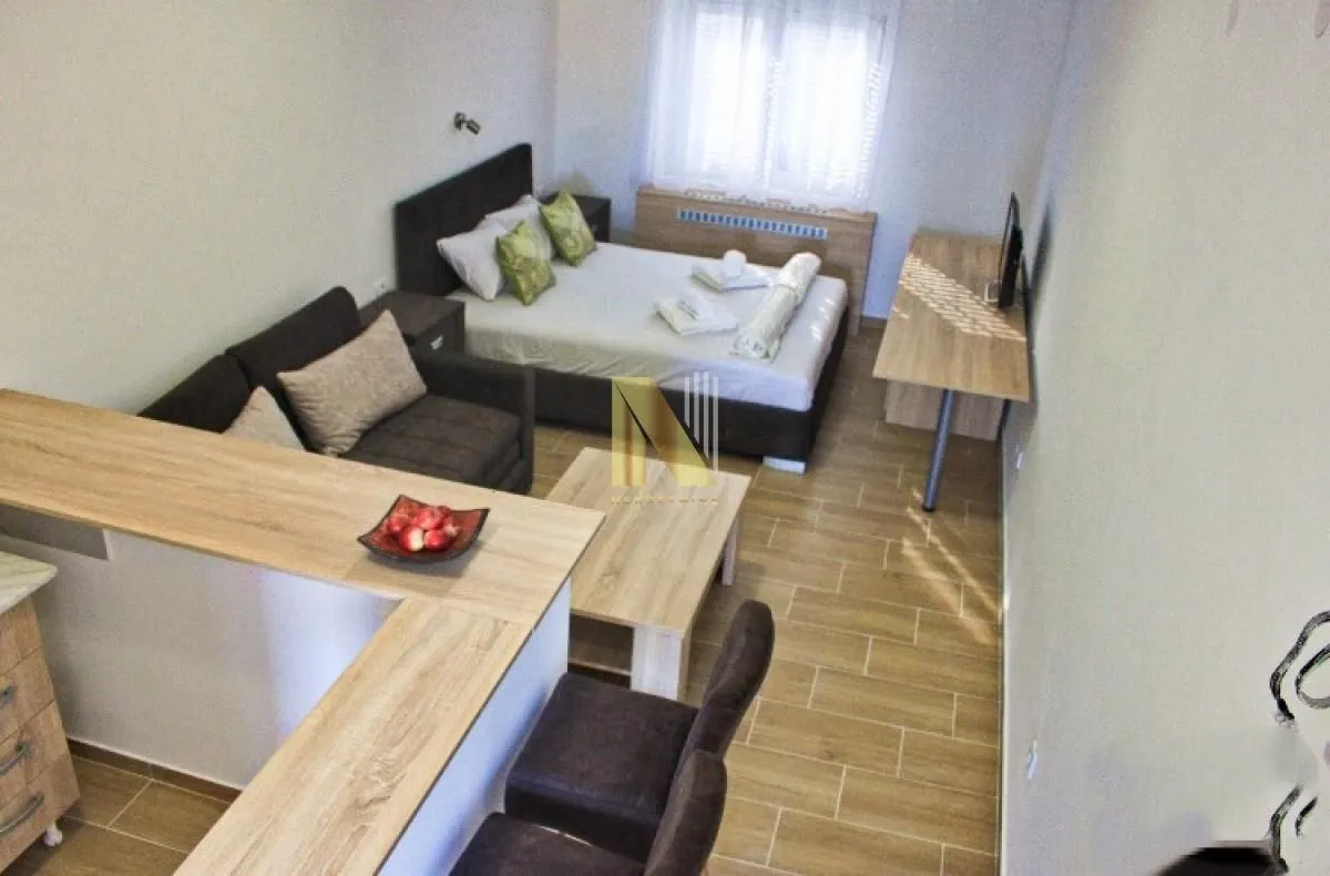 High-angle view of a furnished studio apartment with a bed, sofa, and breakfast bar.