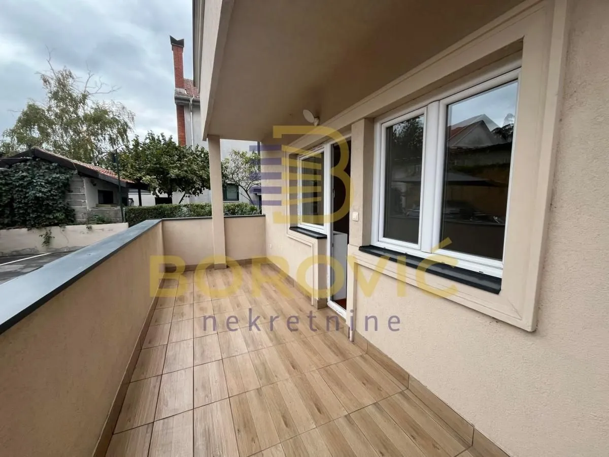 Prostrani popločani balkon sa pogledom na dvorište i okolne objekte.