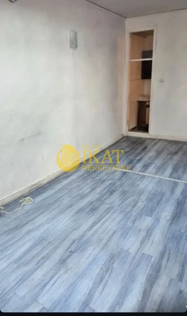 Empty room with grey laminate flooring and white walls.