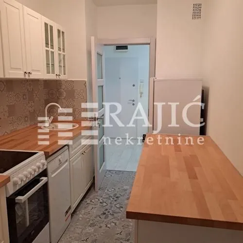 Small kitchen with white cabinets and a wooden countertop.