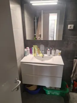 Manje kupatilo sa umivaonikom, ogledalom i tamnim pločicama. - image 11