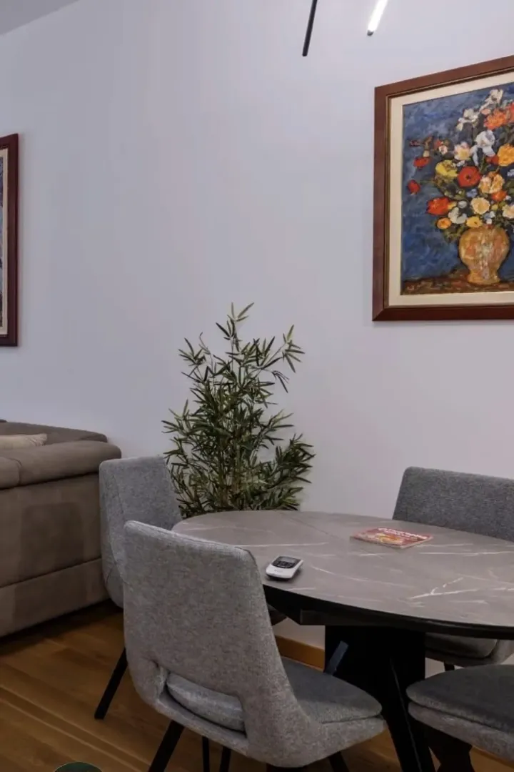 Trpezarijski sto sa stolicama i umjetničkom slikom na zidu.