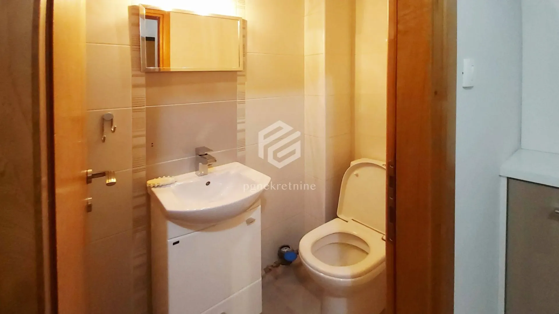 Smaller bathroom with a sink, mirror, and toilet.