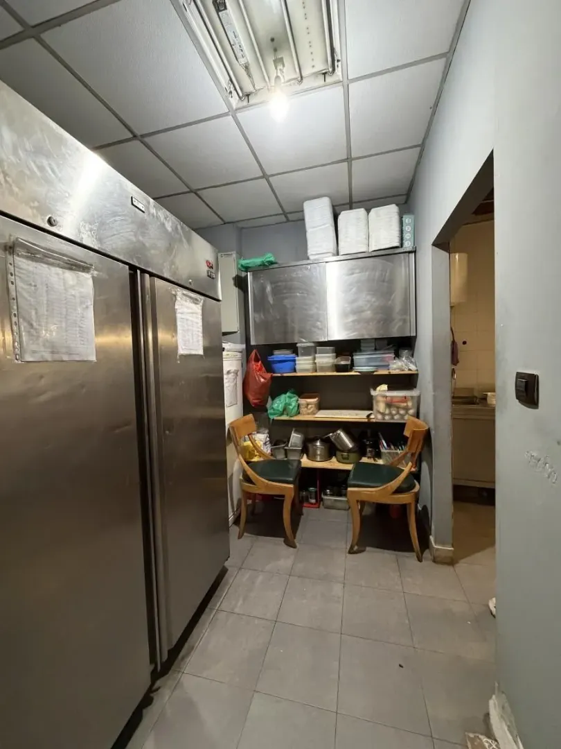 Commercial kitchen with a large refrigerator, metal cabinets, and shelves.