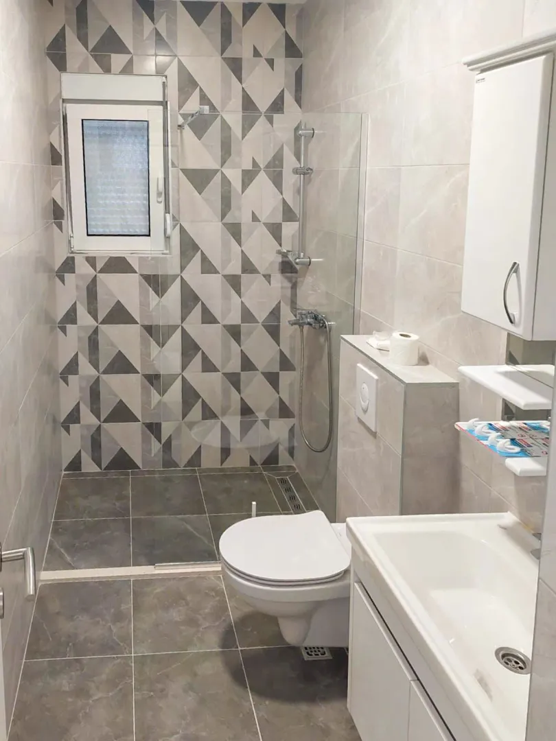 Kupatilo sa tuš kabinom, umivaonikom i ugradnom wc šoljom.
