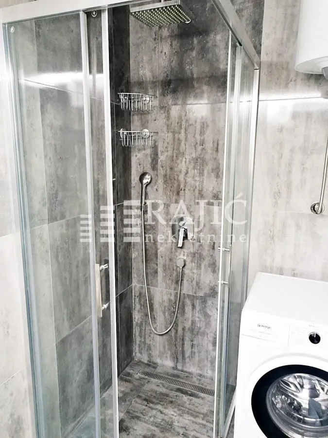 Modern bathroom with a shower cabin and ceramic tiles.