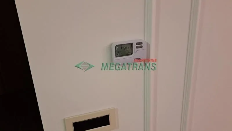 Termostat na belom zidu sa prekidačem.