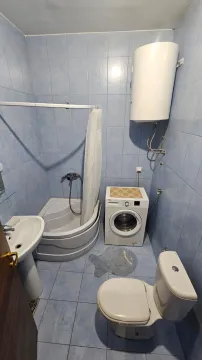Manje kupatilo sa plavim pločicama, tuš kabinom, umivaonikom, veš mašinom i toaletom. - image 19