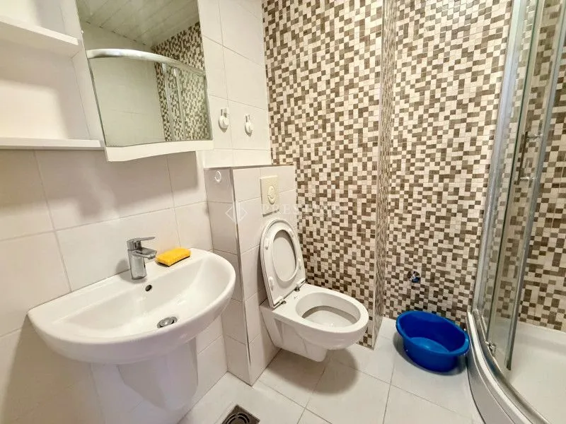 Manje kupatilo sa umivaonikom, WC šoljom i tuš kabinom.