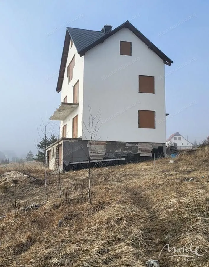 Pogled na spoljašnjost trospratne kuće u izgradnji sa okolinom.