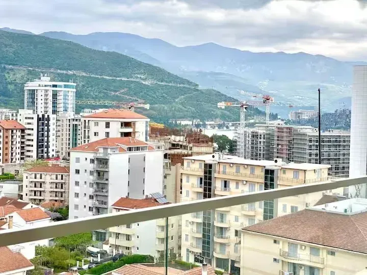 Pogled sa terase na gradski pejzaž i planine u pozadini.