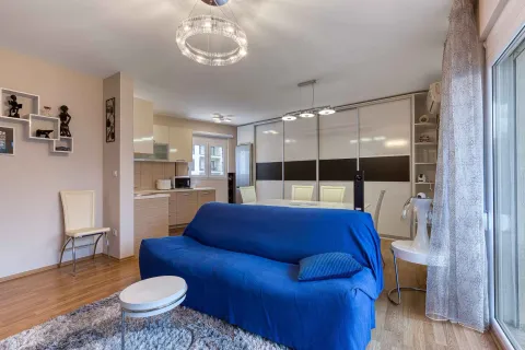 Living room with a blue sofa, dining area, and kitchen in the background. - image 9