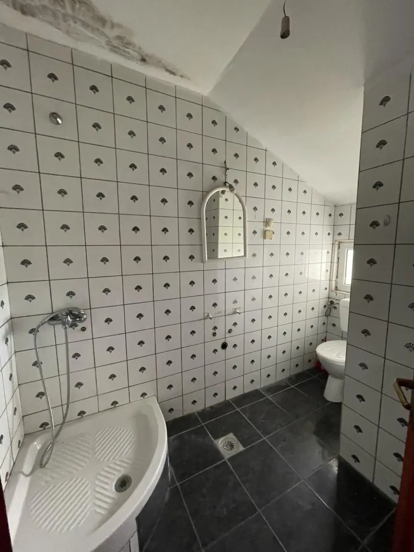 Kupatilo pod kosinom sa tuš kadom i pločicama.