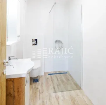 Bright modern bathroom with a walk-in shower and sink. - image 11