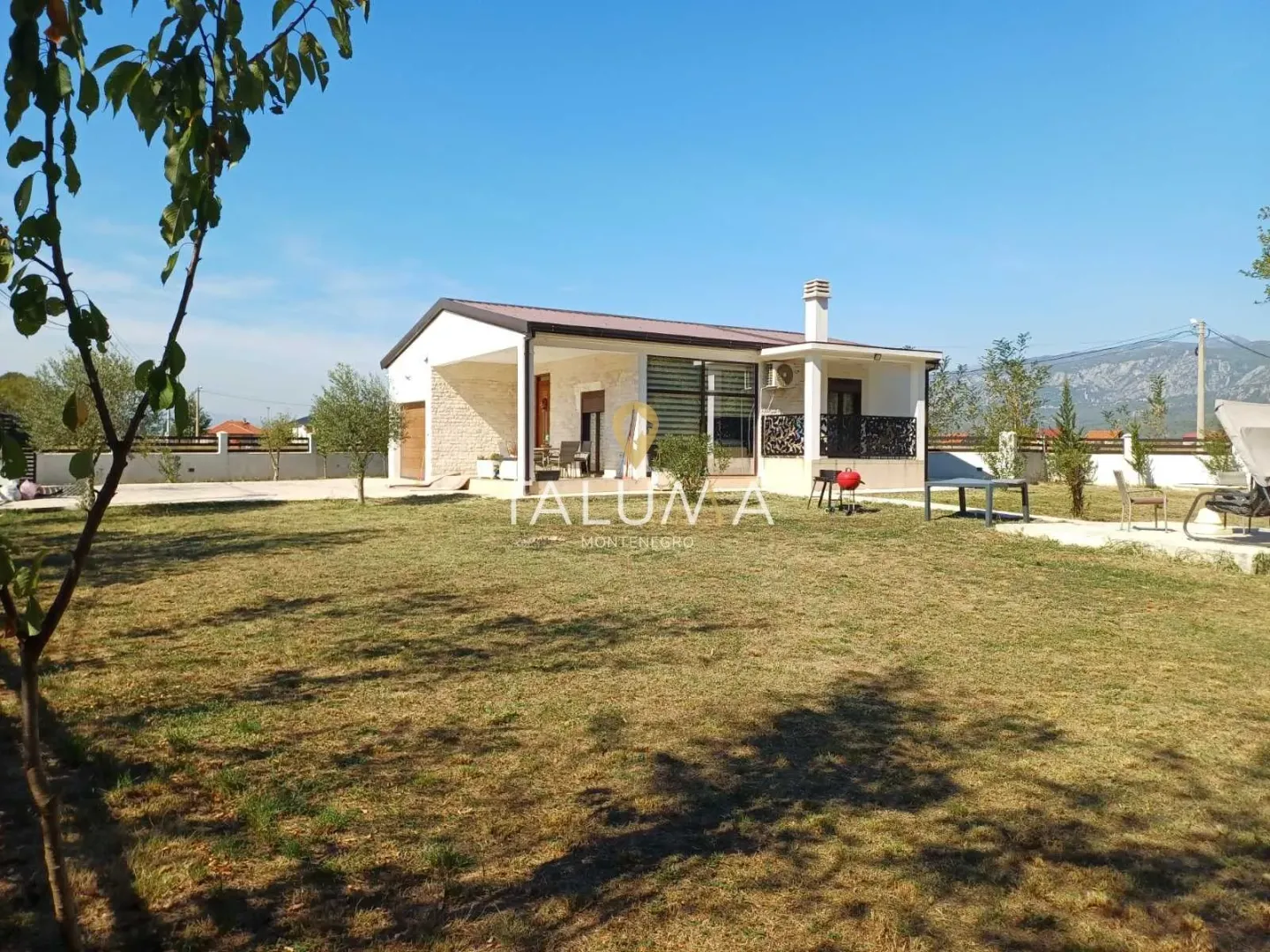 View of the yard and a single-story house with a terrace.