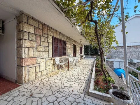 Prostrana popločana terasa ispred kuće sa garniturom za sjedenje i lozom. - image 5