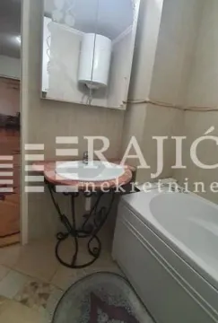 Smaller bathroom with a washbasin, bathtub, and water heater. - image 7