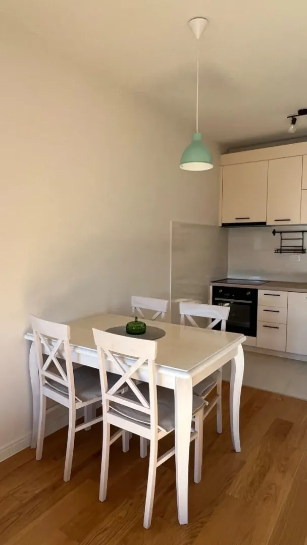 Trpezarija sa trpezarijskim stolom i stolicama, povezana sa kuhinjom.