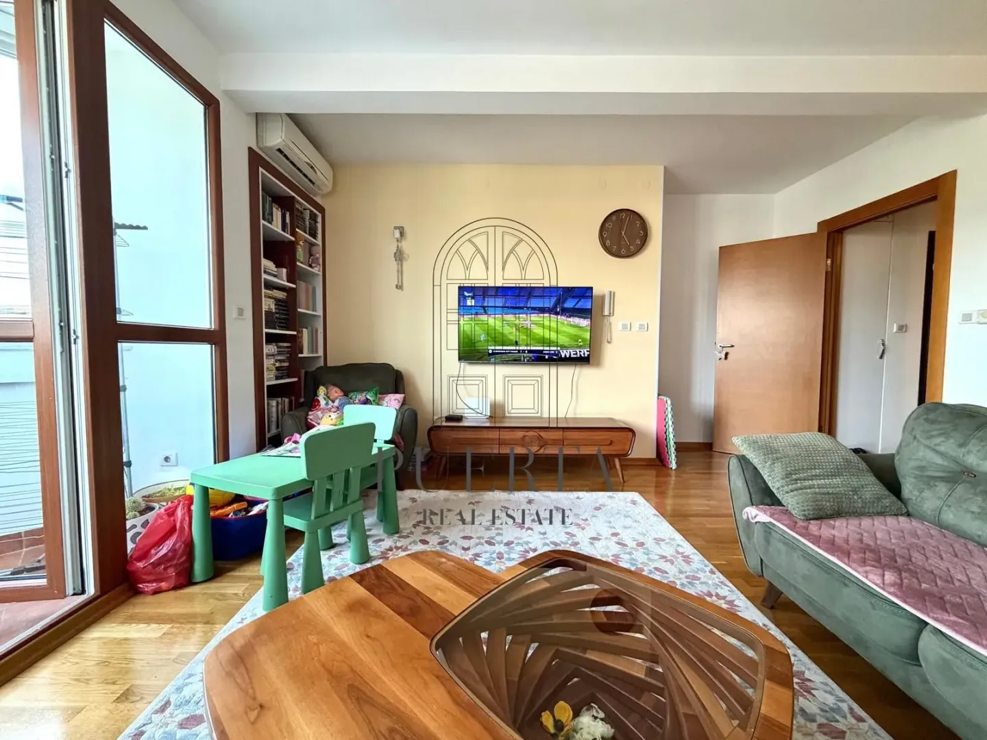 Dnevna soba sa garniturom, televizorom i trpezarijskim stolom za djecu.