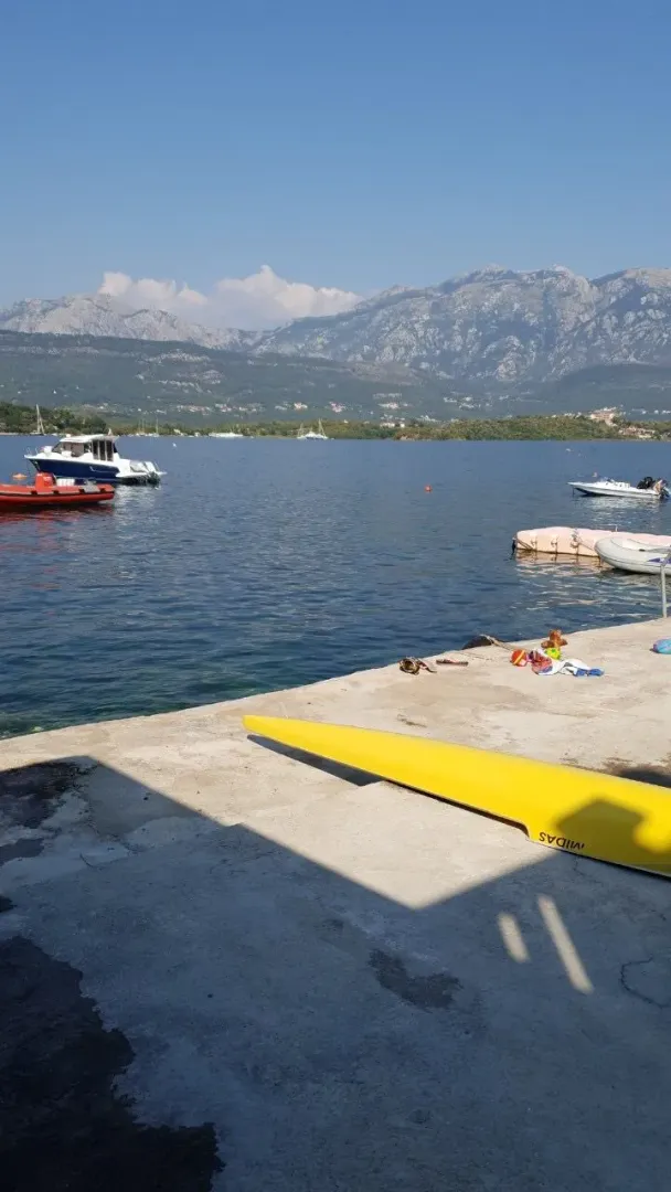 Pogled na more i planine sa betonskog pristaništa sa čamcima.