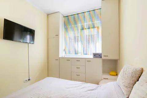Manja spavaća soba sa krevetom, ugradnim ormarima i televizorom na zidu. - image 12