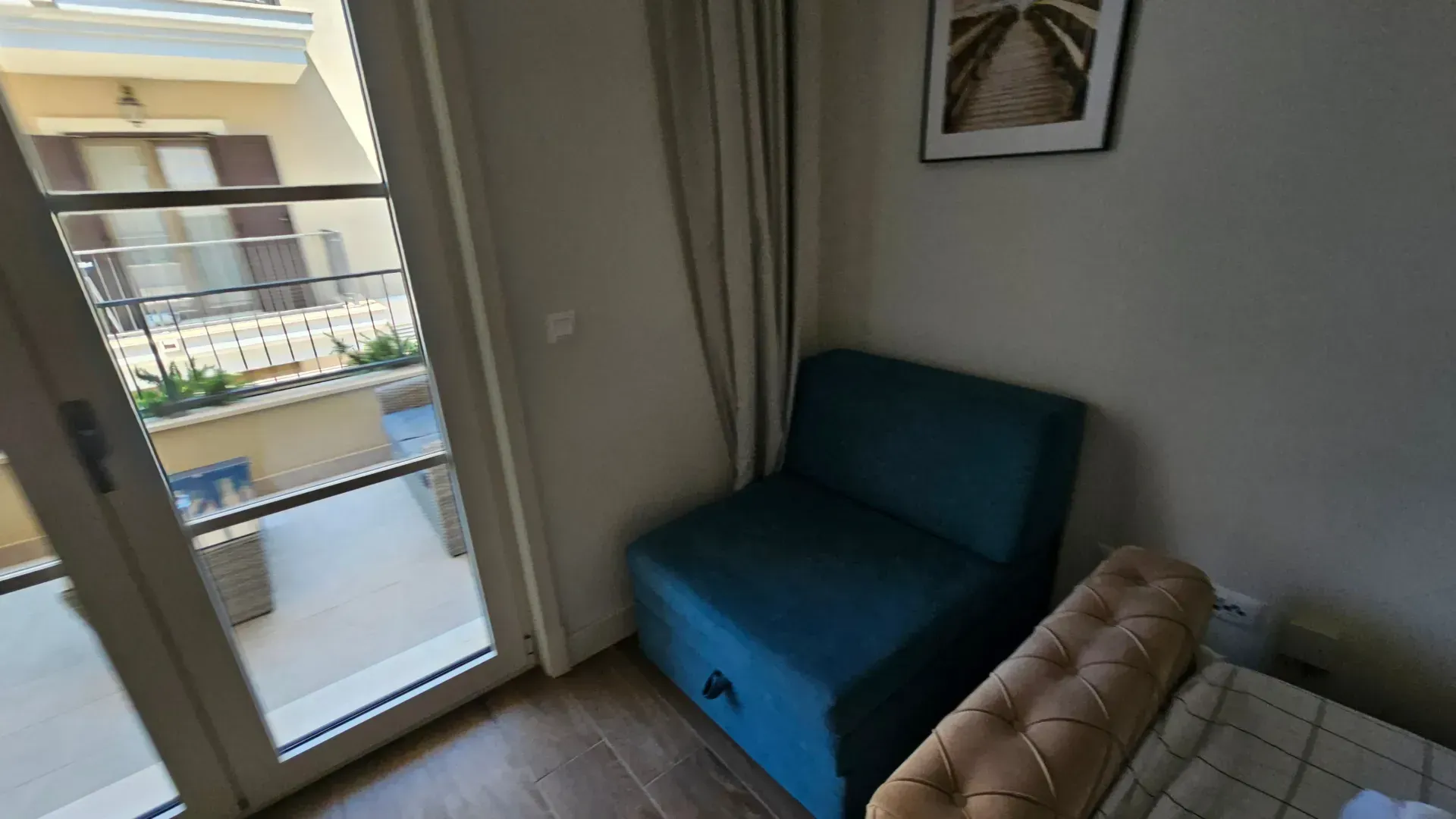 Manja spavaća soba sa plavom foteljom i izlazom na terasu.