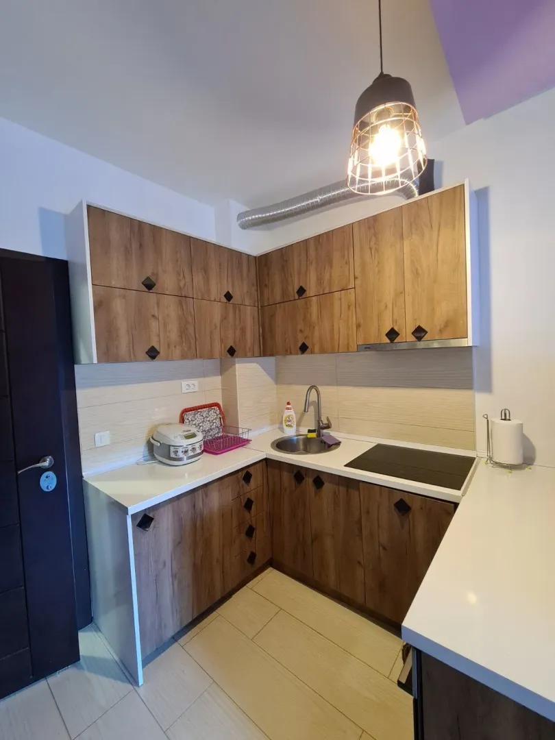 Small kitchen with wooden cabinets, sink, and built-in stovetop.