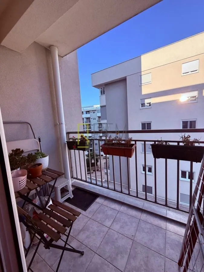 Small furnished balcony with a table, chairs, and flowers.