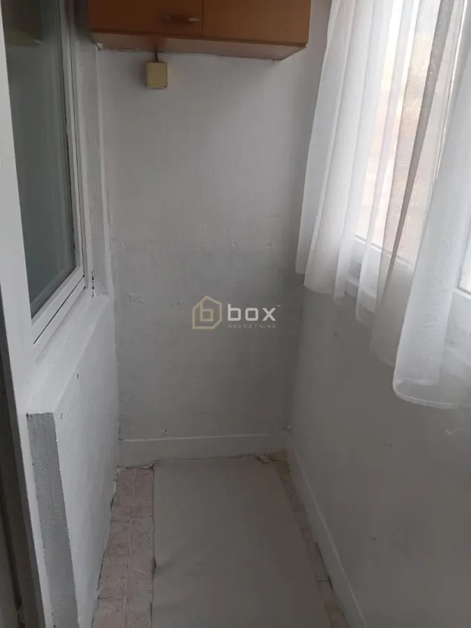 Pogled na zatvoreni balkon sa prozorima i zavesama.