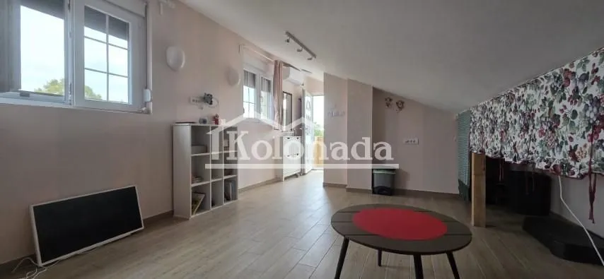 Dnevna soba sa kosim plafonom, policama i stočićem.