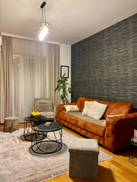 Comfortable living room with a brown sofa, coffee tables, and a decorative wall. - image 4
