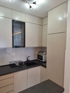 Moderna kuhinja sa bijelim elementima i tamnom radnom površinom. - image 8