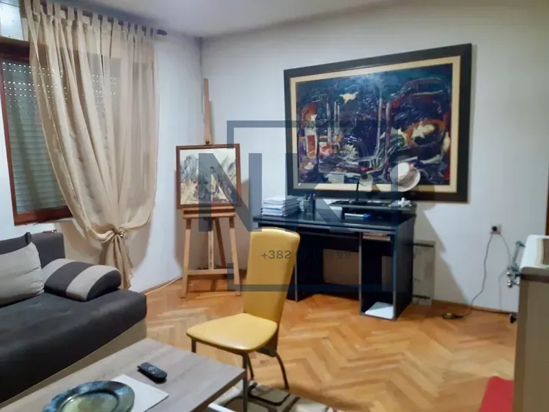 Dnevna soba sa garniturom, radnim stolom i slikarskim štafelajem.