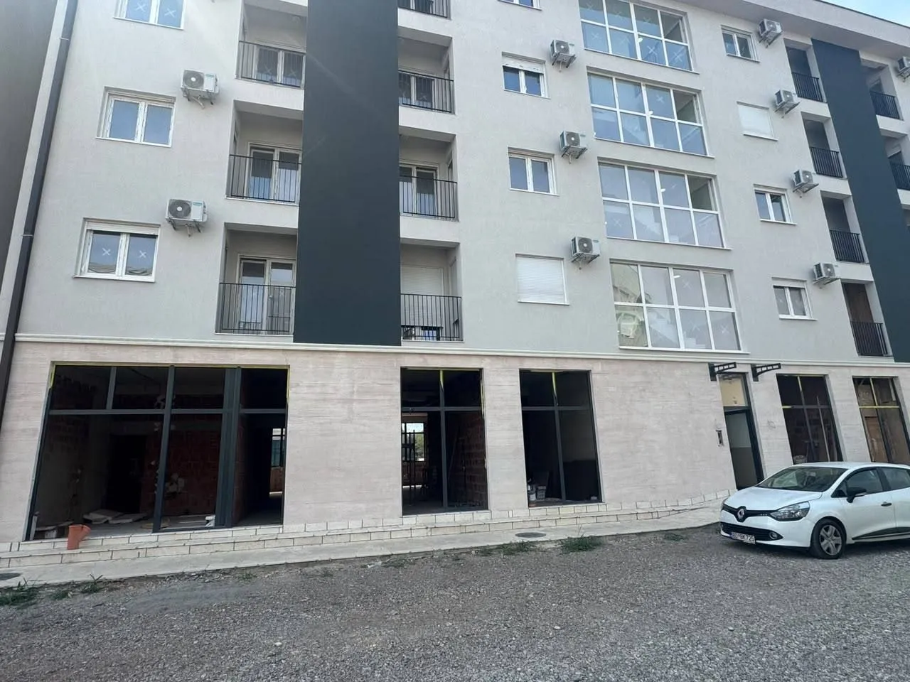 Exterior view of a multi-storey residential building with commercial space on the ground floor.