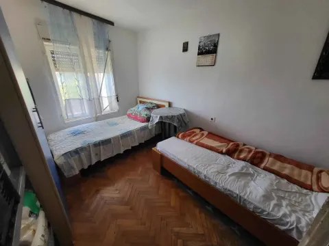 Spavaća soba sa dva kreveta, parketom i prozorom sa zavjesama. - image 4