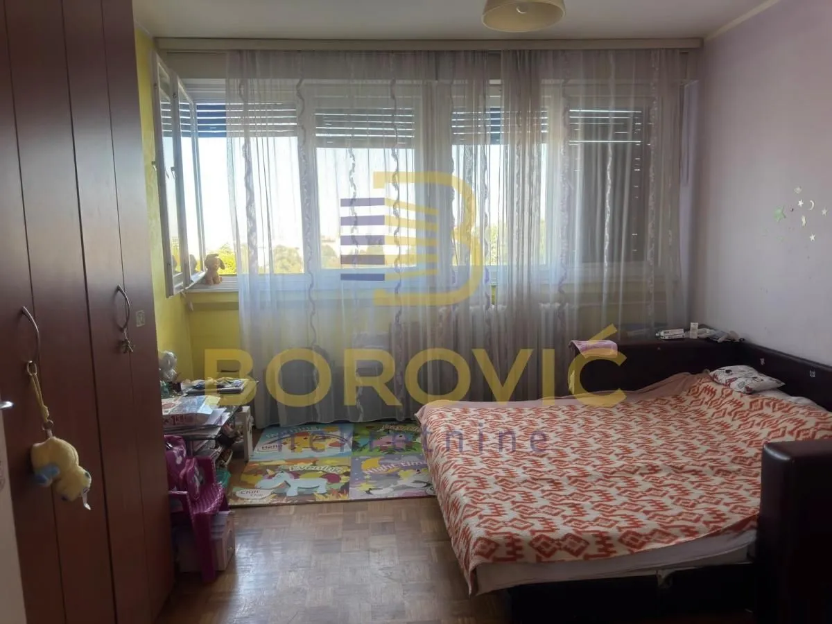 Nameštena spavaća soba sa krevetom i velikim prozorom.