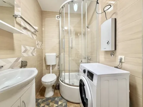 Kupatilo opremljeno tuš kabinom, WC šoljom, umivaonikom i veš mašinom. - image 5