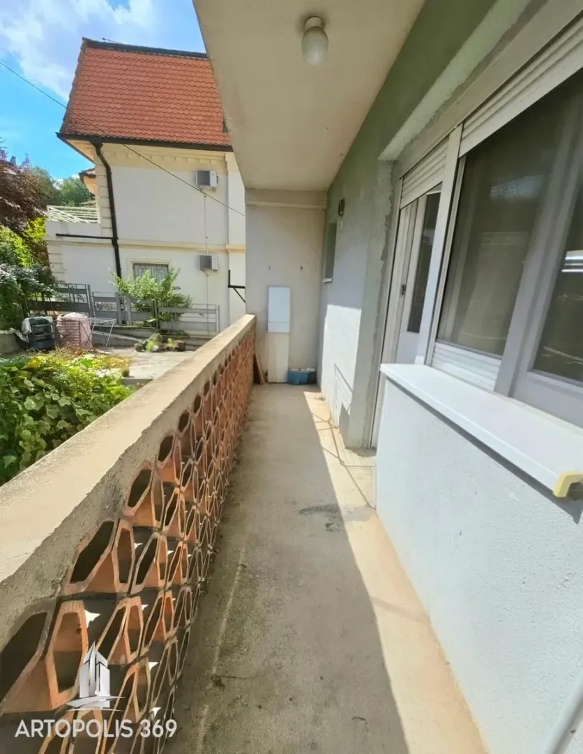 Natkriveni balkon sa pogledom na dvorište i okolne kuće.