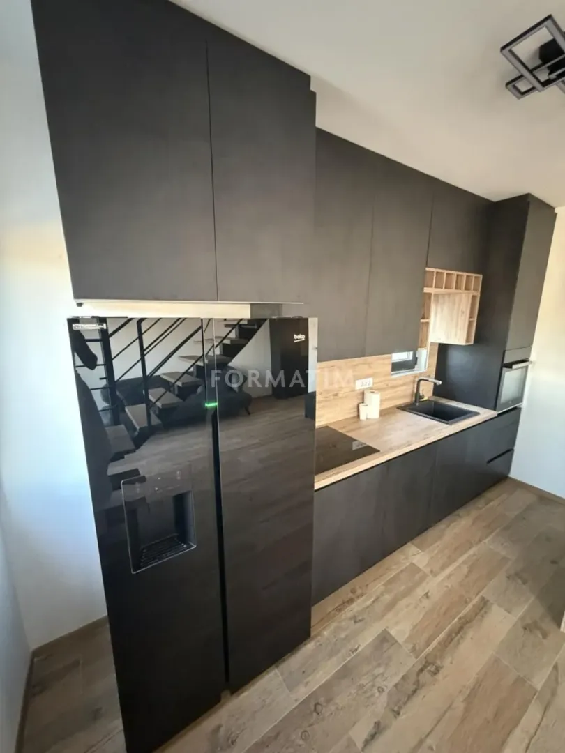Modern dark kitchen with built-in appliances and wooden details.