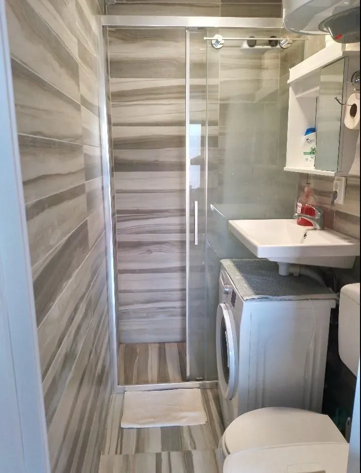 Small bathroom with a shower cabin, sink, and washing machine.