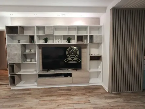 Living room with a large wall shelving unit, television, and wooden paneling. - image 8