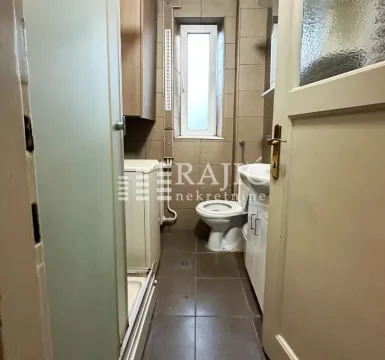 Smaller bathroom with a shower cabin, sink, and toilet. - image 9