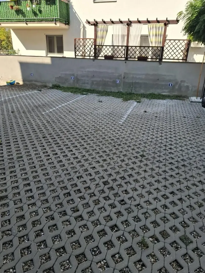 Ograđeni spoljni parking prostor sa obeleženim parking mestima.