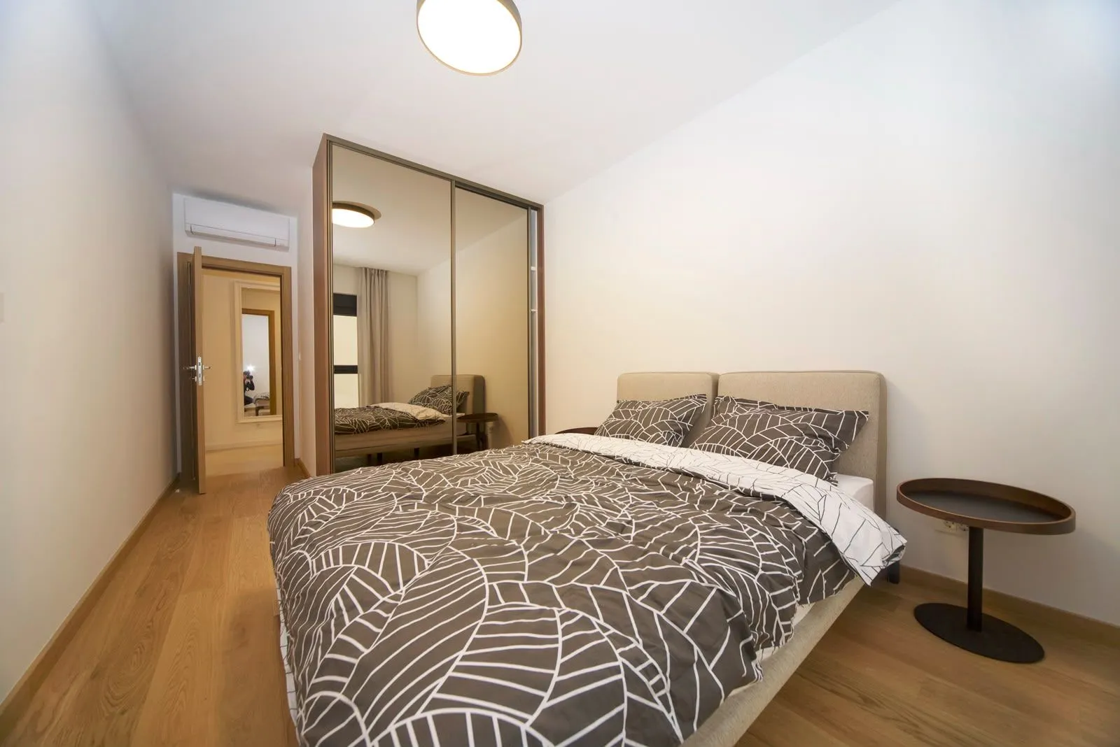 Furnished bedroom with a double bed, large wardrobe and wooden flooring.