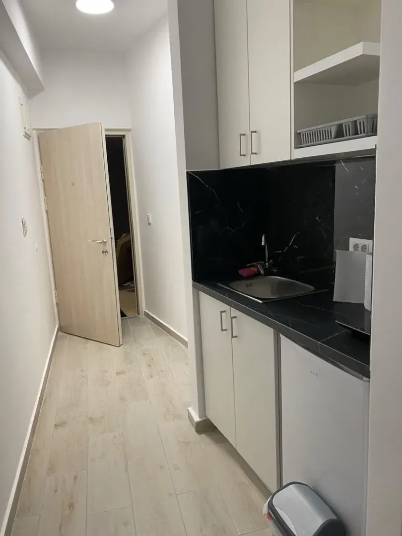 Manja kuhinja u hodniku sa crnom radnom pločom i bijelim elementima.