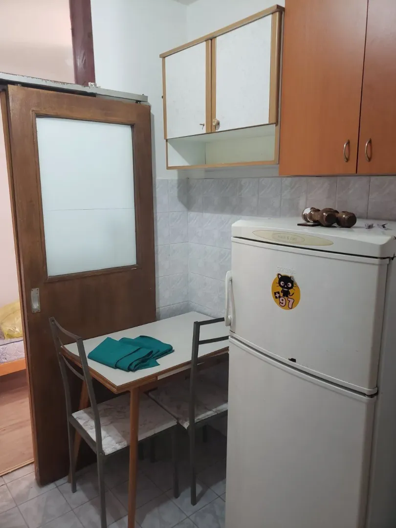 A small kitchen featuring a dining table, chairs, and a refrigerator.