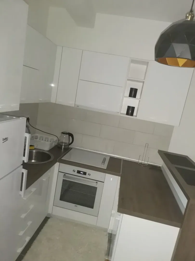 Small kitchen with white cabinets and built-in appliances.